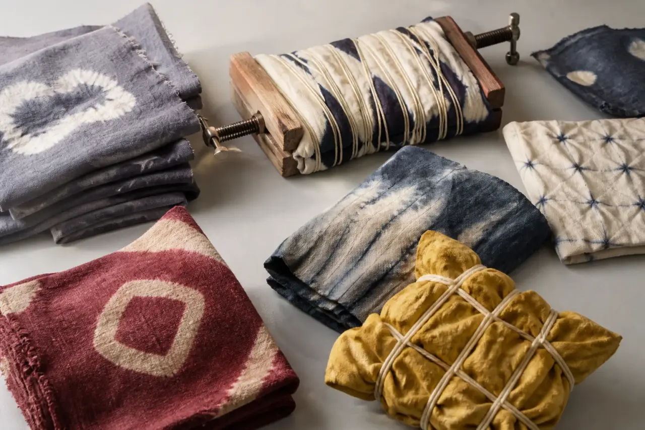 Distinct resist-dyed cloth samples arranged on a pale studio table