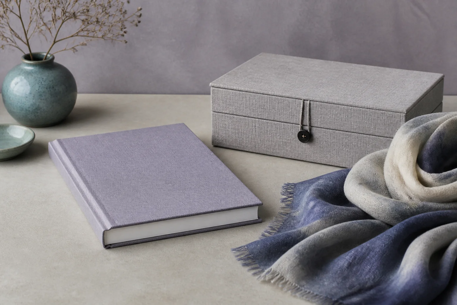 Closed cloth-bound notebook beside a lidded archival textile box