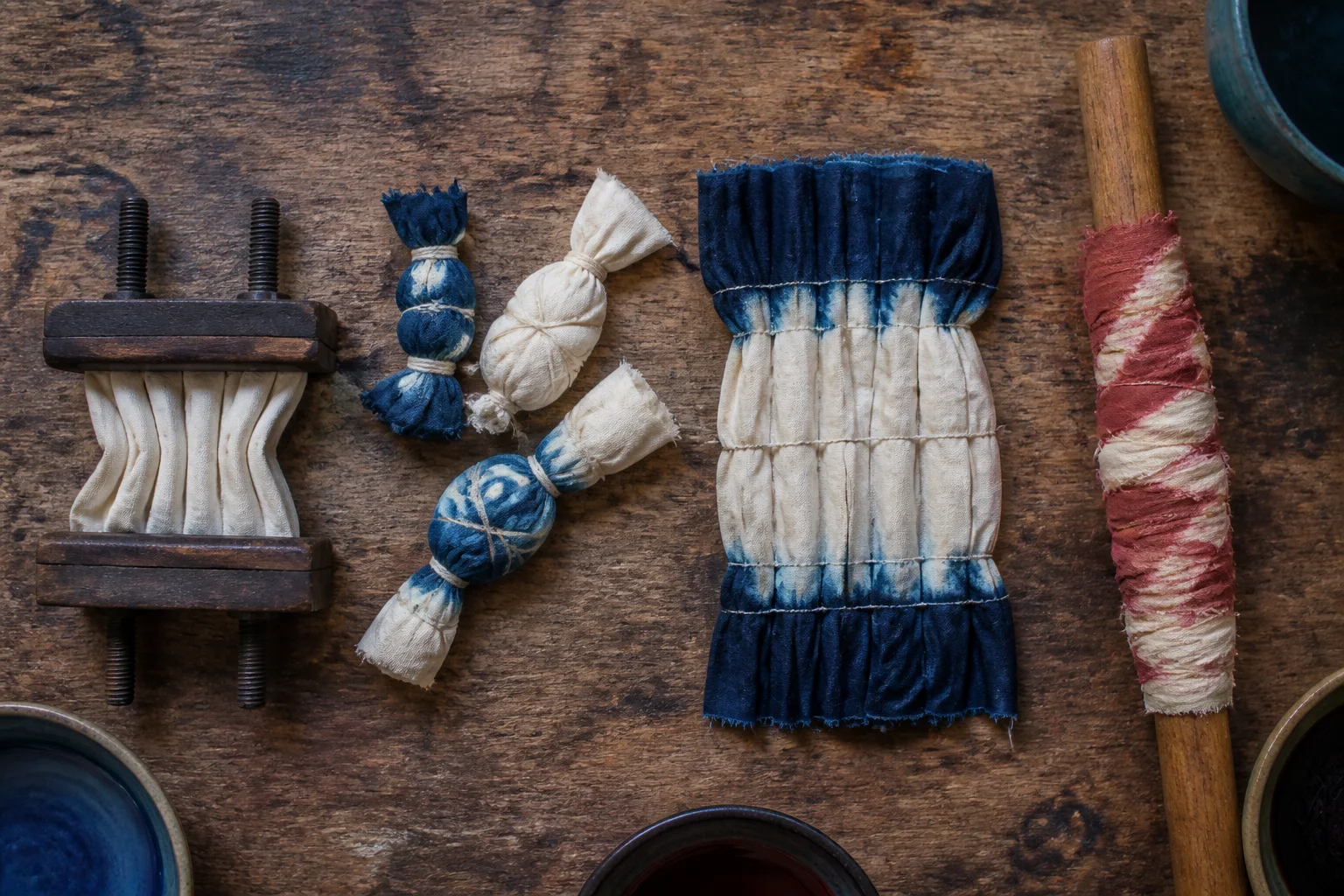 Folded, tied, stitched and pole-wrapped cloth samples on a studio table